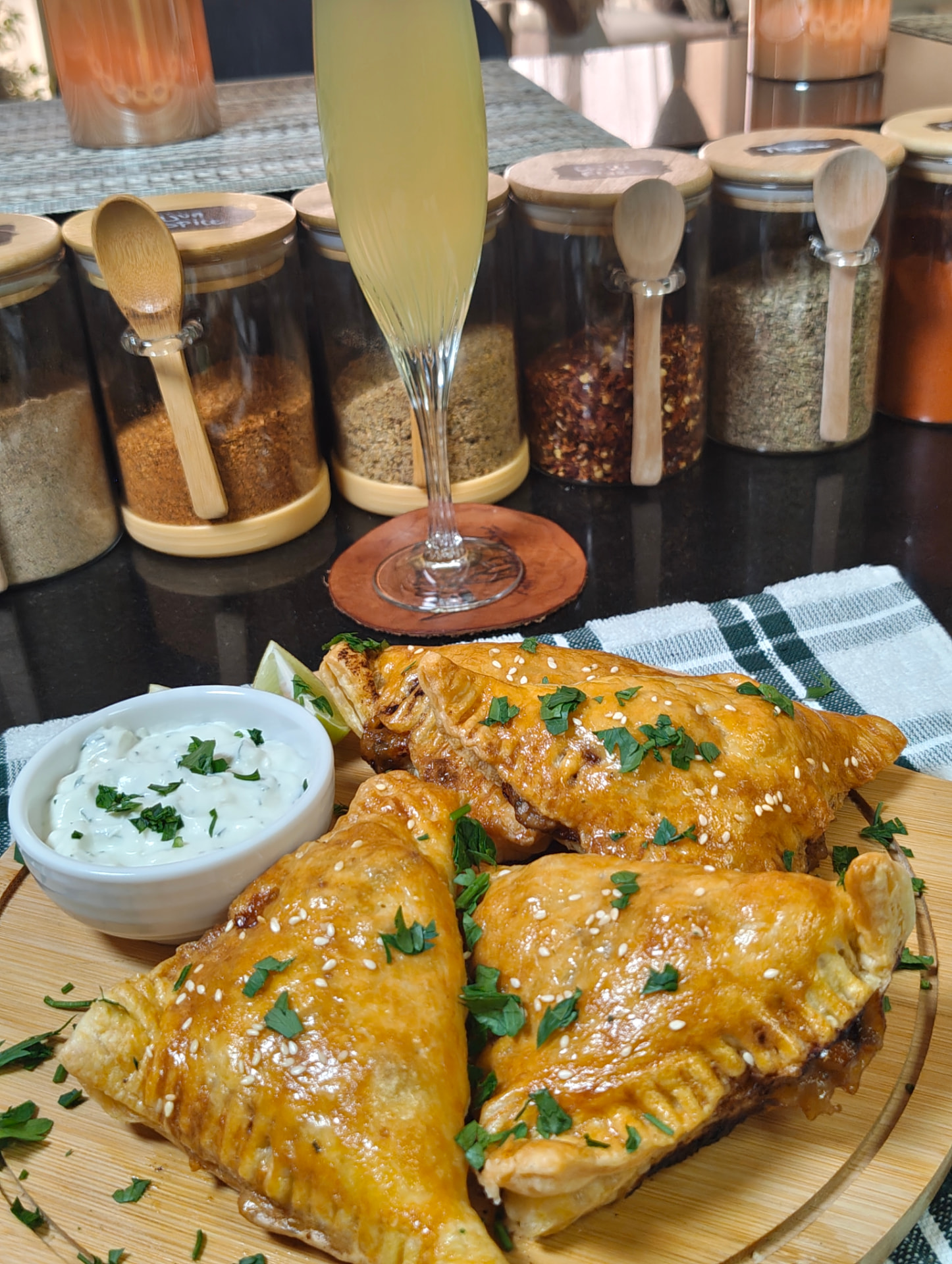 Beef and cheese pastries on a wooden board with garlic sauce, lemon and a drink