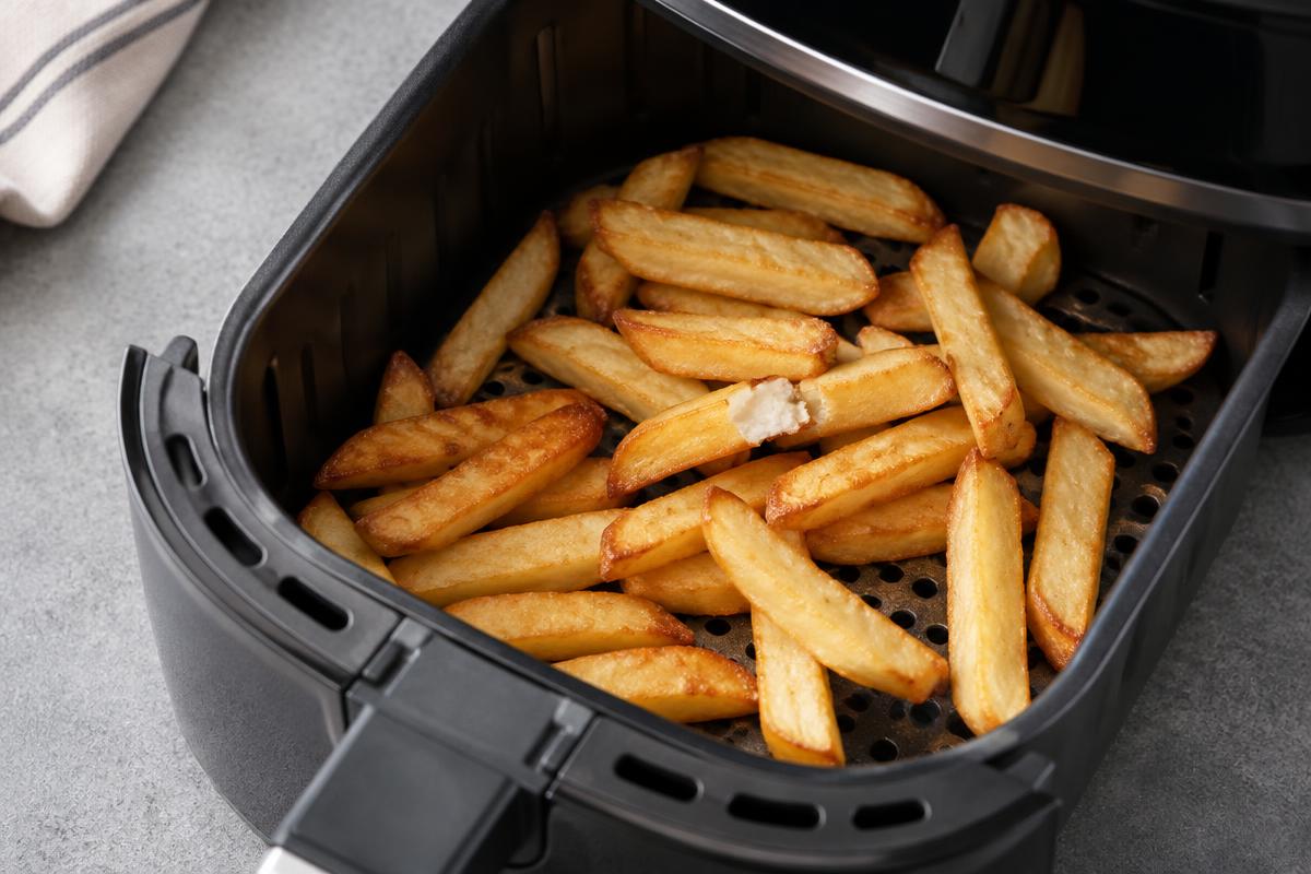 Editorial illustration of golden chips in a perforated air fryer basket