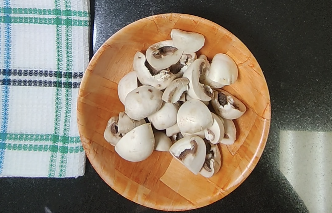 Prepared mushroom halves and pieces on a wooden plate