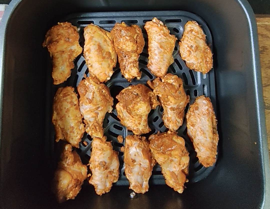 Seasoned raw chicken wings arranged in a single layer in the air fryer basket