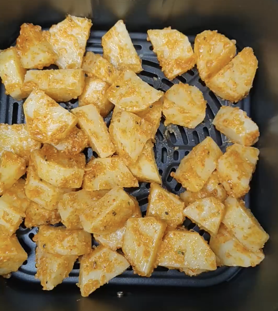Seasoned potato cubes spread in the COSORI Dual Blaze air fryer basket