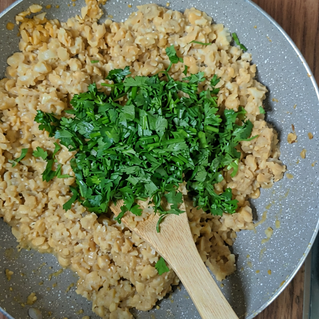 Chicken and quinoa filling cooking in a pan with chopped fresh parsley and a wooden spoon