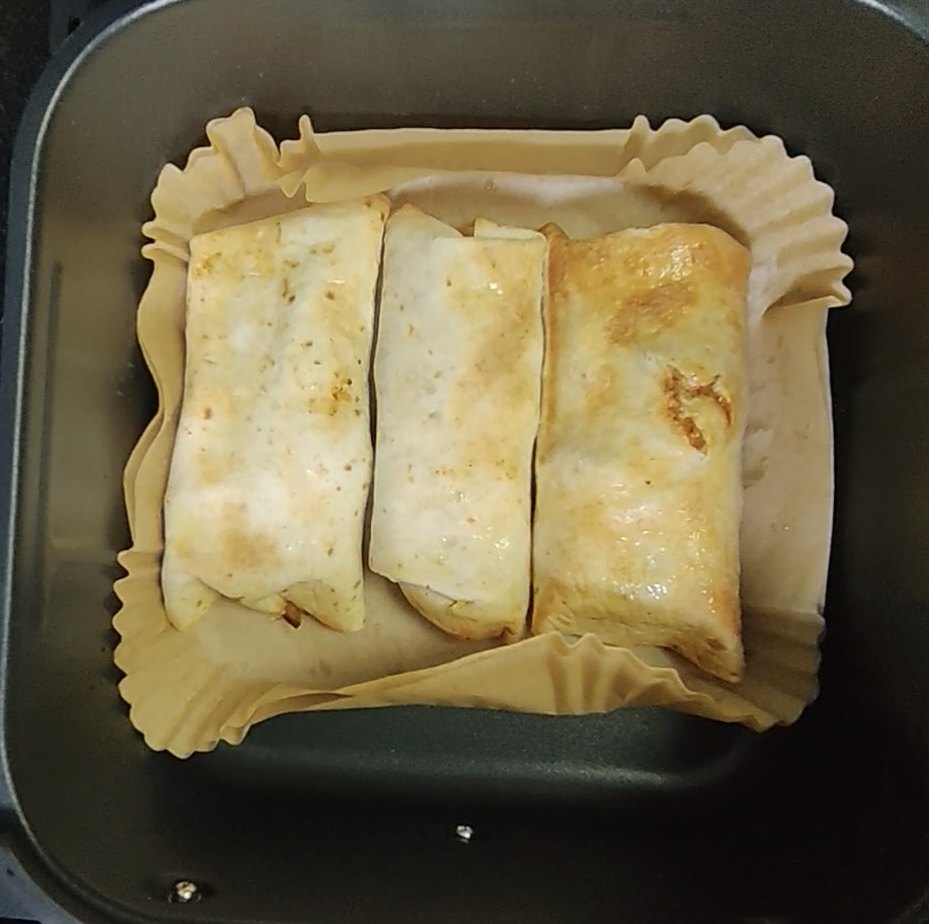 Three golden chicken fajita wraps side by side in the air fryer basket