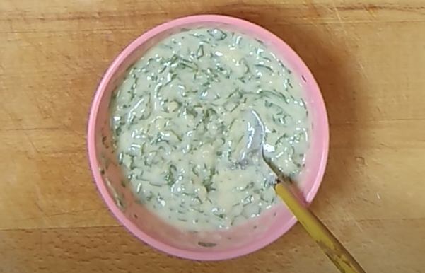 Homemade parsley garlic butter in a small pink bowl with a spoon