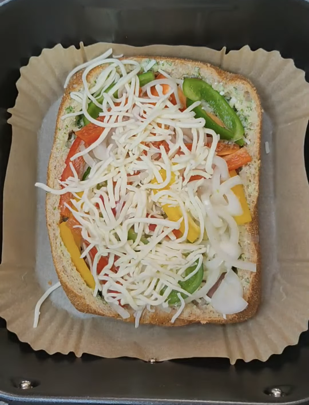 Assembled country bread with mozzarella, peppers and onion in the air fryer basket