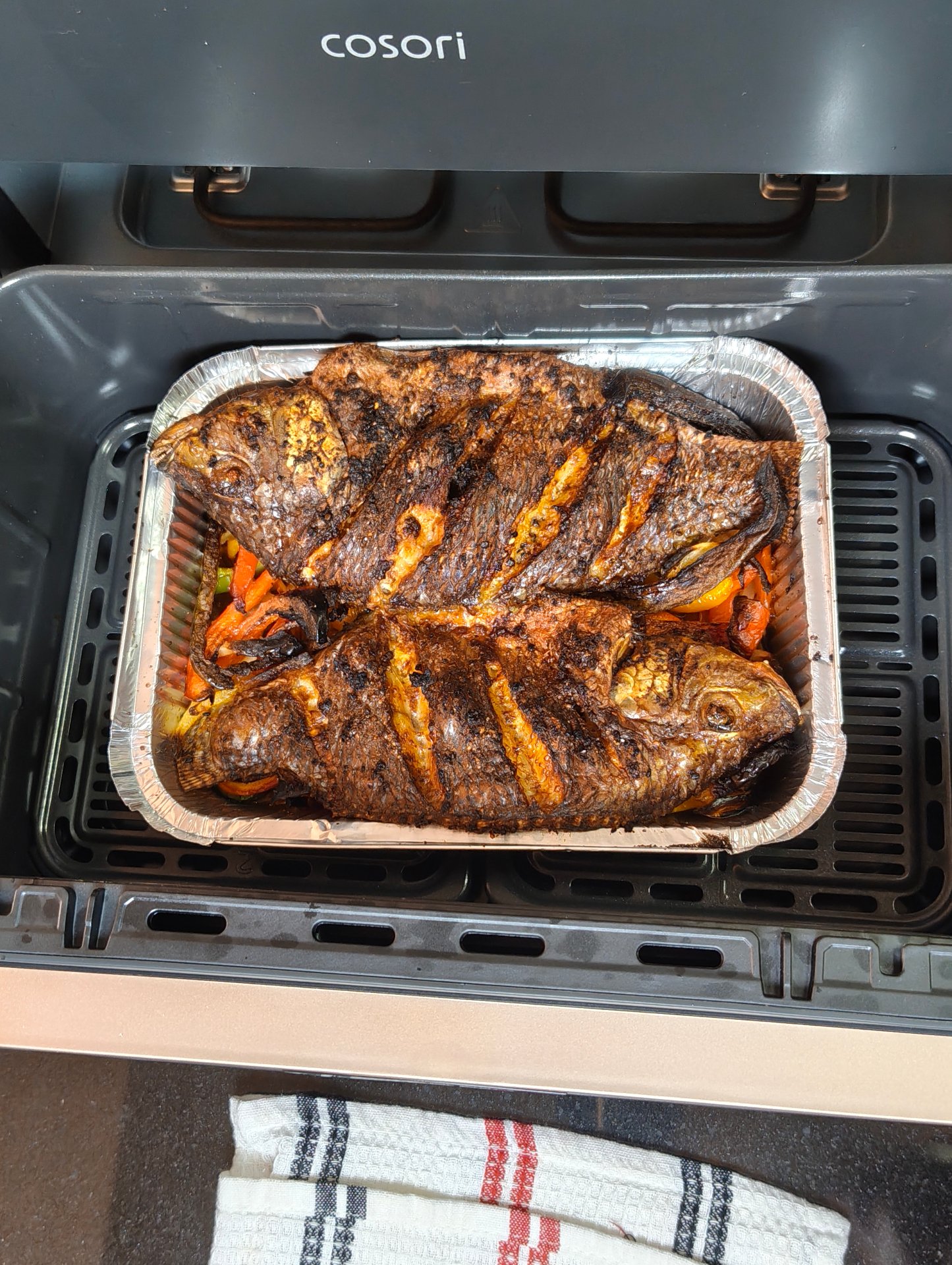Whole tilapia with peppers and onion inside an air fryer basket