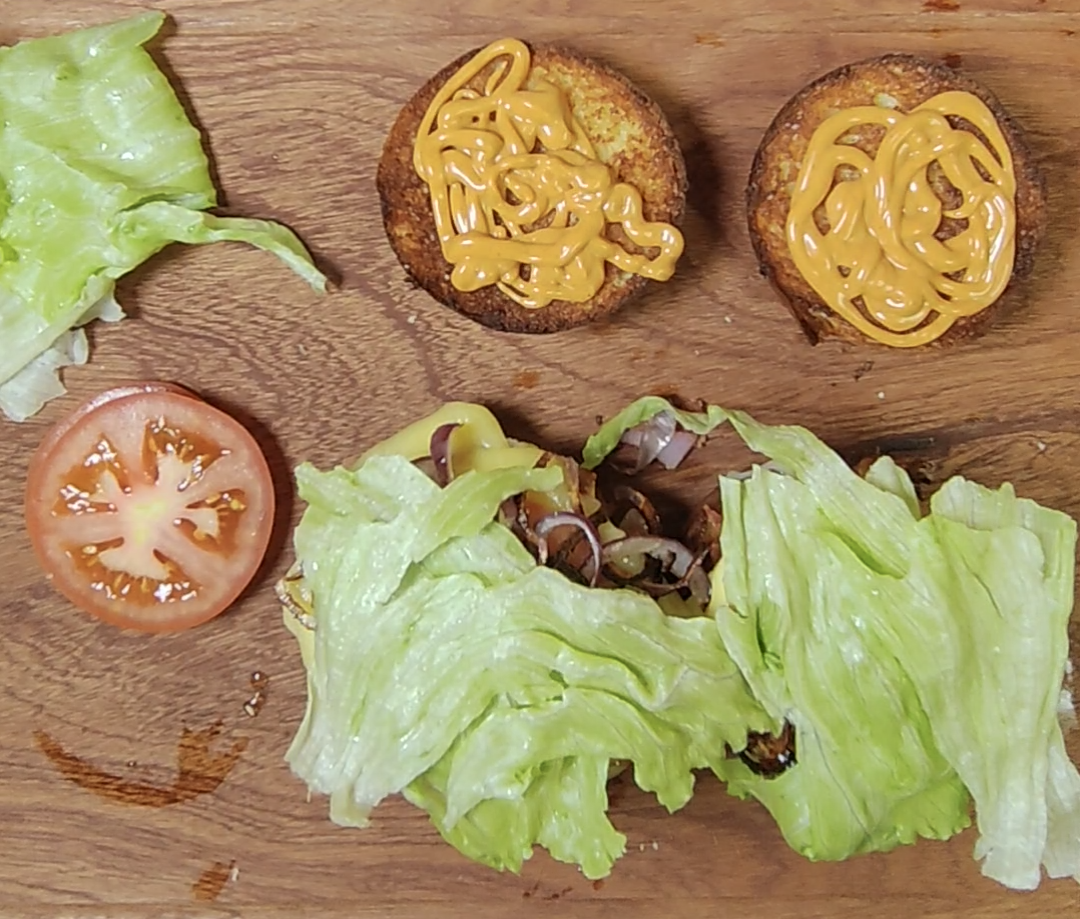 Toasted top buns with hamburger sauce beside the assembled sandwiches topped with fresh lettuce