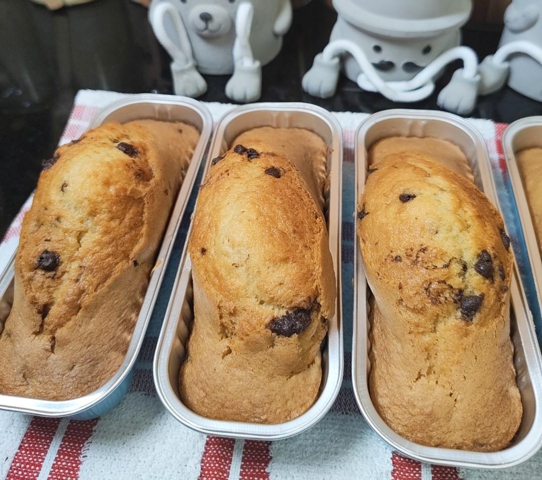 Six risen, golden mini chocolate chip cakes in their tins inside the air fryer drawer