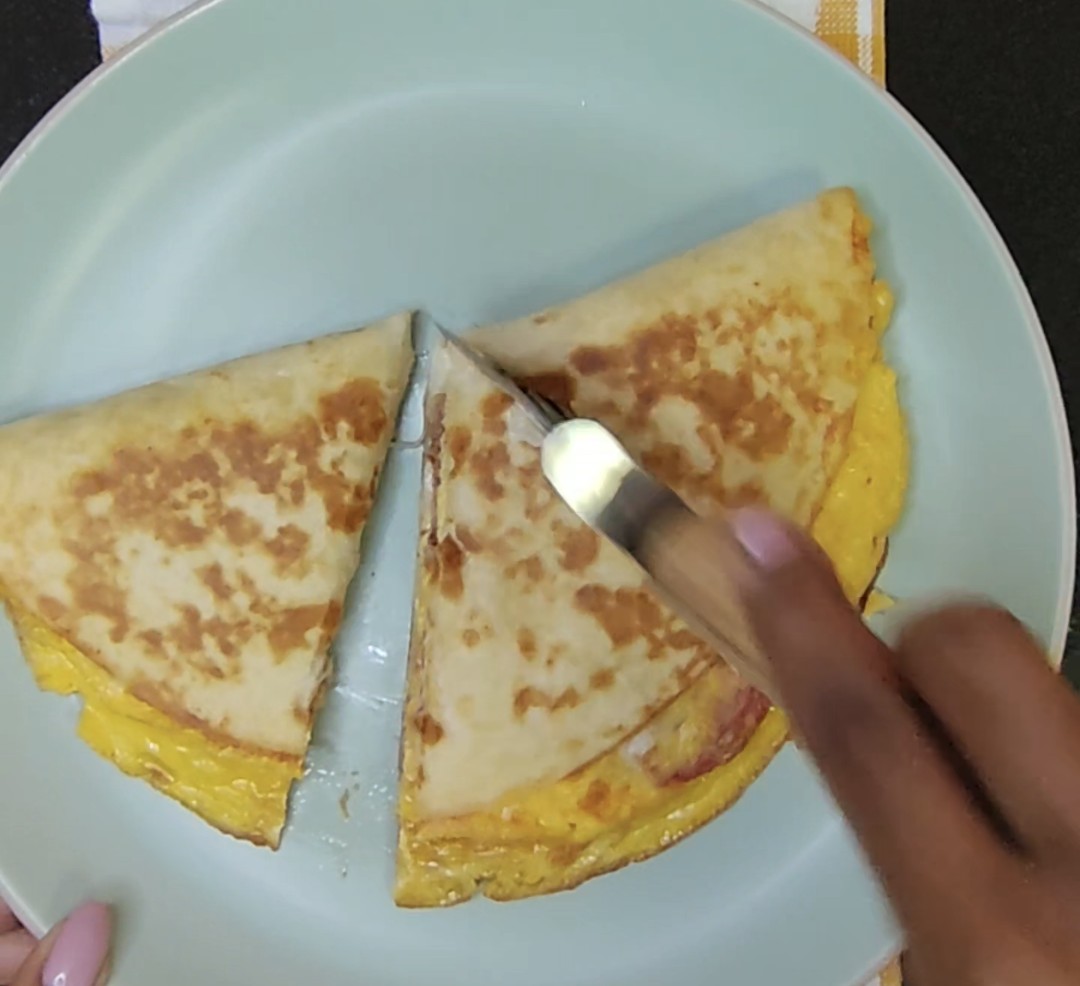 Golden folded breakfast tortilla being cut into portions