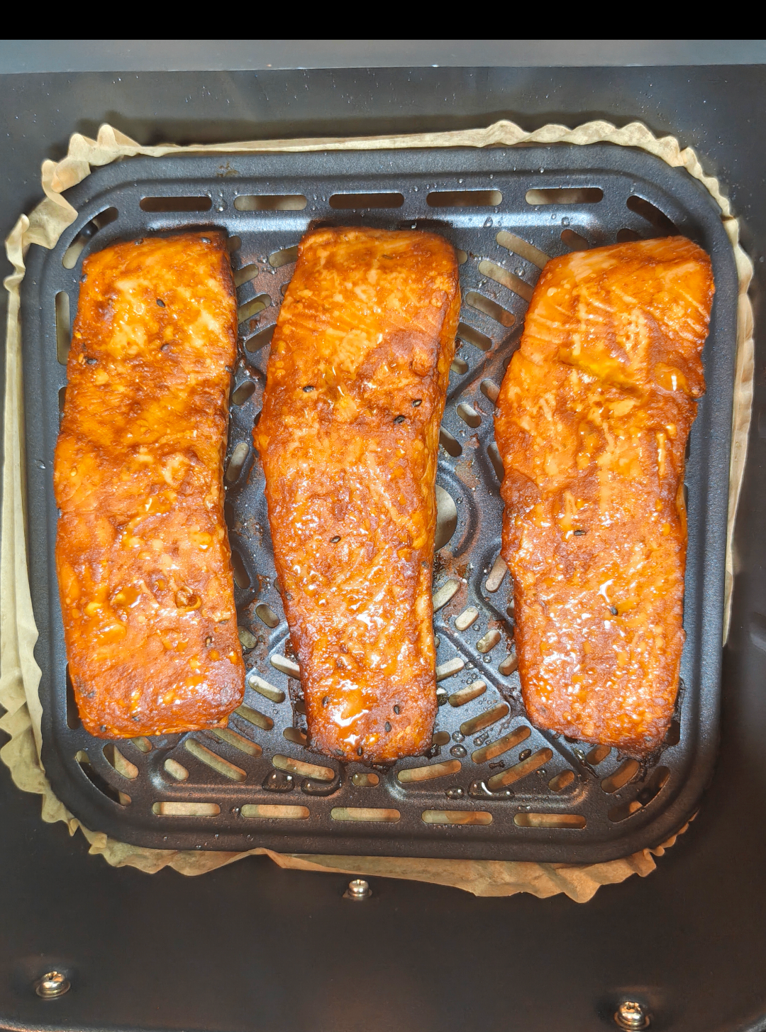 Cooked salmon portions in an air fryer basket