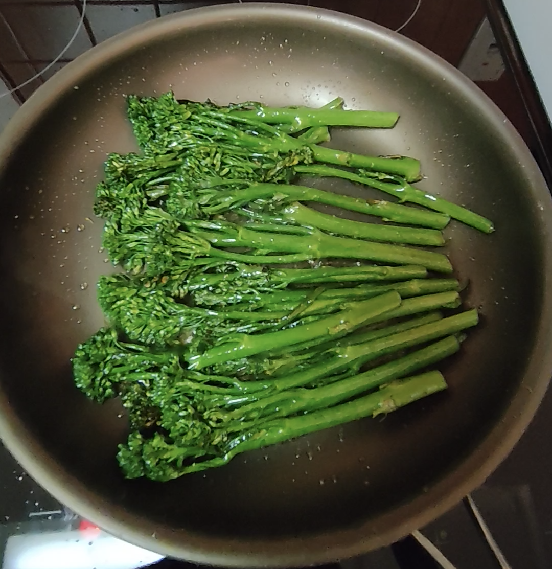 Tenderstem broccoli cooking in olive oil in a frying pan