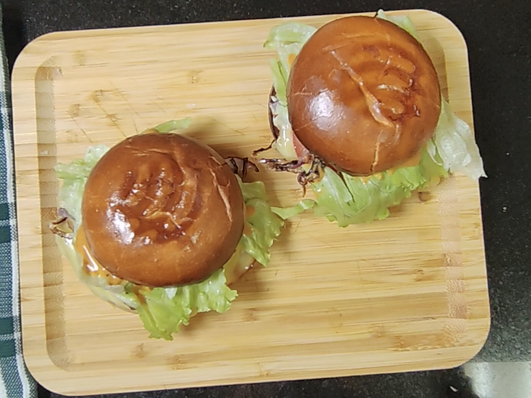 Two finished breakfast sandwiches on a wooden board with lettuce peeking out