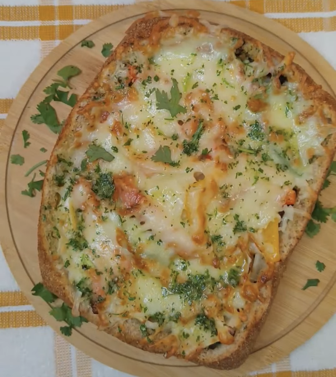 Finished cheesy country bread with golden melted mozzarella on a wooden serving board