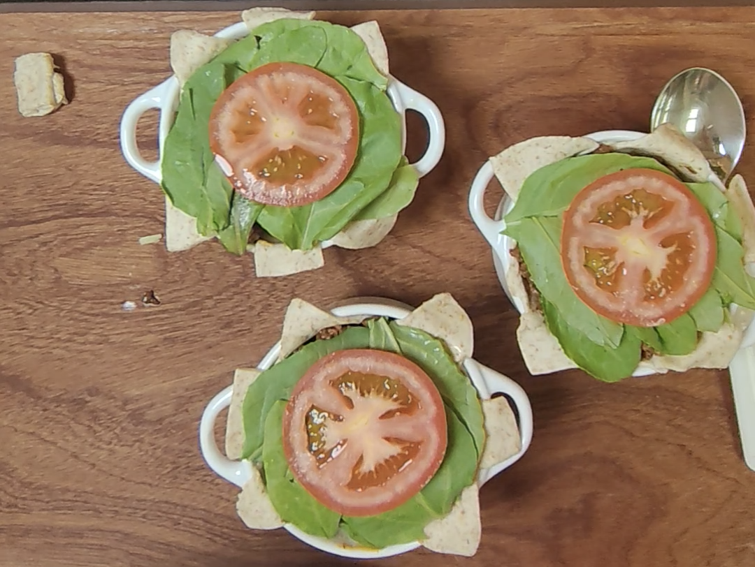 Three filled wholemeal pastry pots topped with fresh spinach and final tomato slices before air frying