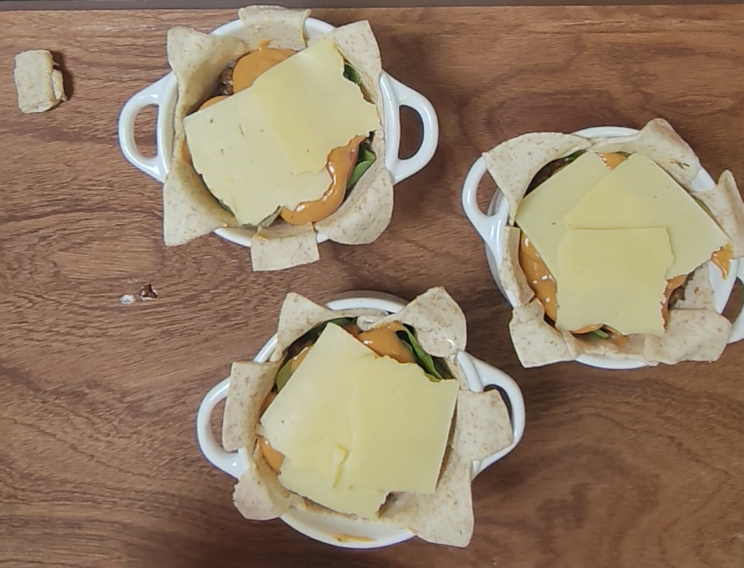 Cheddar cheese slices layered over the filling in three wholemeal pastry pots