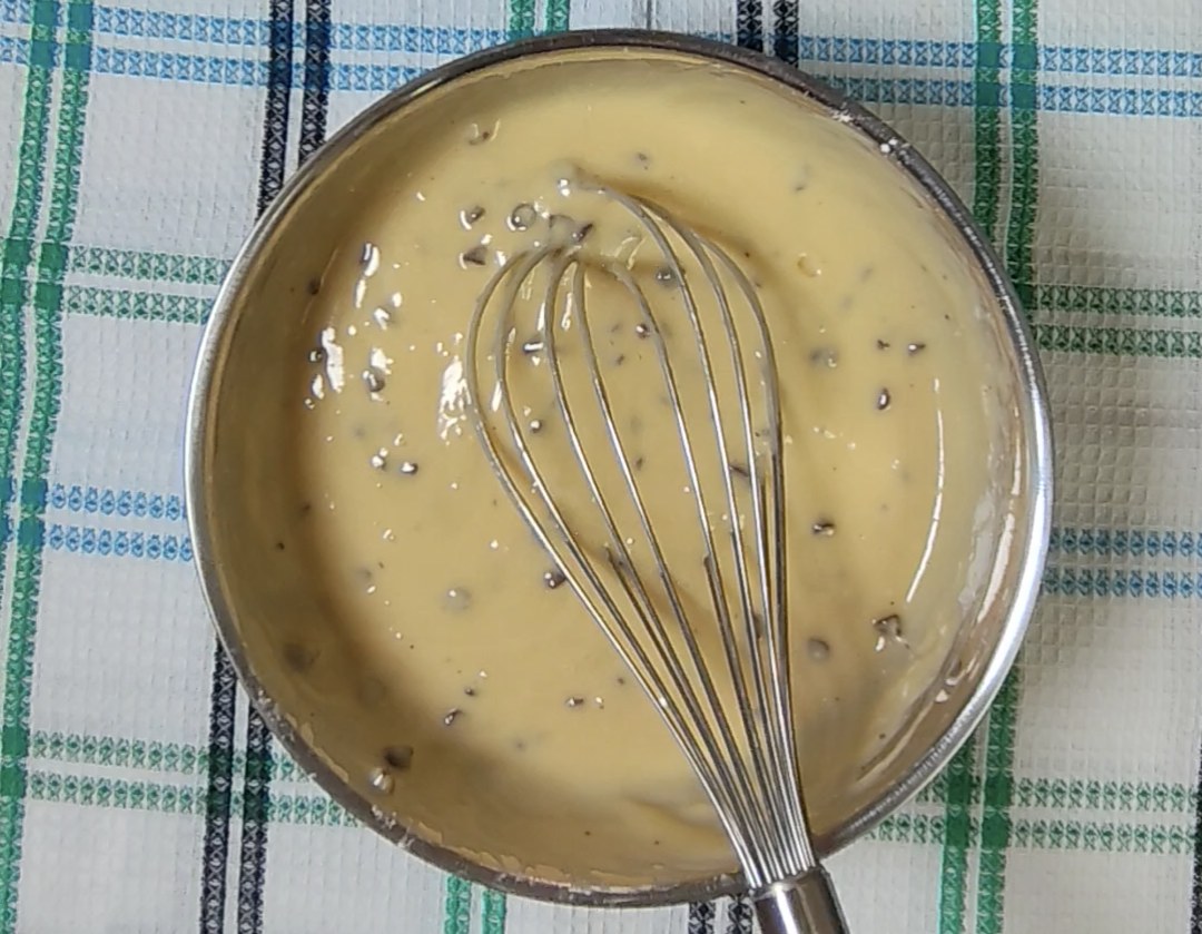 Smooth chocolate chip muffin batter in a mixing bowl with a whisk