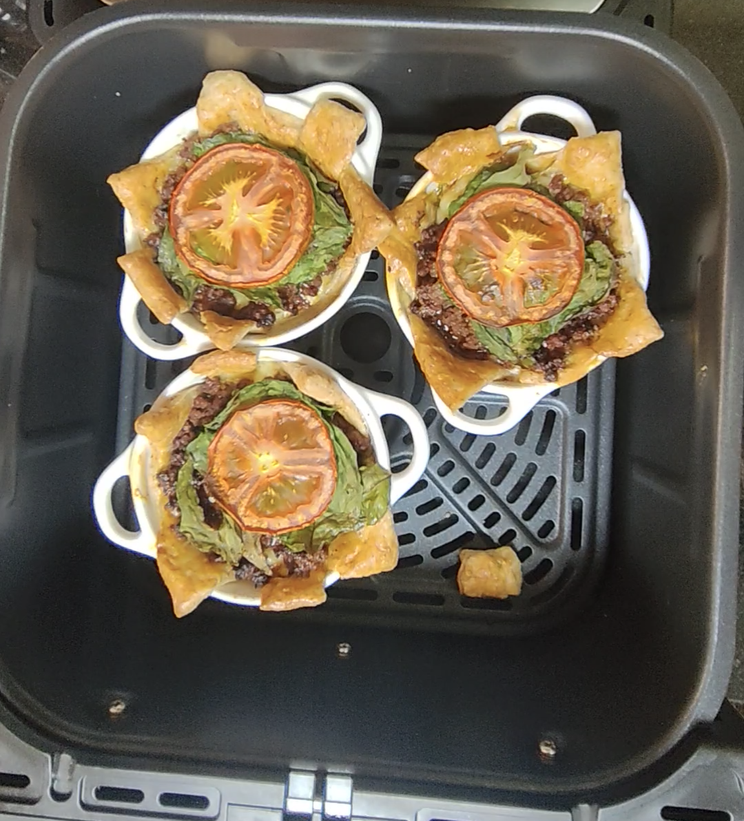 Three pastry pots after the first air fryer cooking stage, with golden pastry edges and softened tomato and spinach, before the mozzarella topping