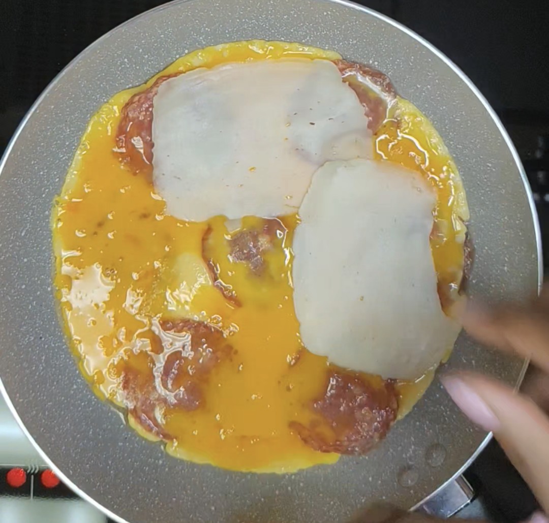 Beaten eggs and salami cooking in a frying pan with mozzarella cheese